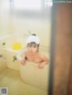 A woman in a bathtub with a towel on her head.