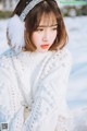 A woman wearing a white sweater and a headband in the snow.