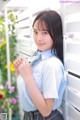 A young woman in a school uniform leaning against a wall.