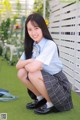 A young woman in a school uniform sitting on the grass.