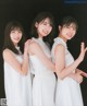 A group of three young women in white dresses posing for a picture.