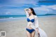 A woman in a blue bikini standing on a beach.