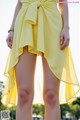 A woman in a yellow dress is posing for a picture.