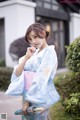 A woman in a blue and white kimono holding an umbrella.