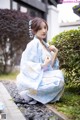 A woman in a blue kimono sitting on the ground.