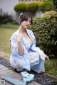 A woman in a blue kimono sitting on the ground.