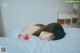 A woman laying on a bed with a strawberry in her hand.