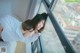 A woman leaning against a window looking out at the city.