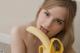 A young woman holding a banana in front of her mouth.