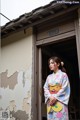 A woman in a kimono standing in front of a door.