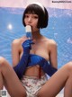 A woman in a bathing suit and blue gloves holding a popsicle.