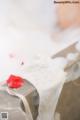 A bathtub filled with white foam and a red rose.