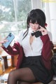 A woman sitting at a desk holding a cell phone.