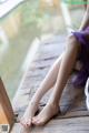 A woman in a purple dress sitting on a wooden floor.