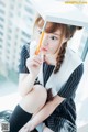 A woman in a graduation cap and gown holding a pencil.