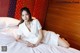 A woman in a white dress laying on a bed.