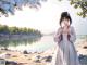 A woman in a white dress standing by a lake.