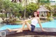 A woman sitting on the edge of a swimming pool.