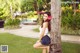 A young woman leaning against a palm tree in a park.