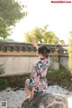 A woman sitting on a rock in a garden.