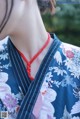 A woman wearing a blue and white kimono with a red necklace.