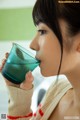 A woman drinking a glass of blue liquid from a cup.