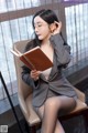 A woman sitting on a chair reading a book.