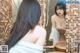 A woman standing in front of a mirror in a bathroom.