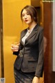 A woman in a business suit holding a glass of water.