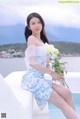 A woman sitting on the edge of a swimming pool holding a bouquet of flowers.