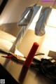 A red candle sitting on top of a desk next to a lamp.