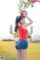 A woman in a red shirt and blue shorts holding a basketball.